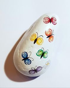 a white painted rock with colorful butterflies on it's side, against a white background