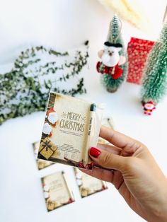 a person holding up a book in front of some christmas decorations and trees on the table