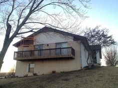 a two story house sitting on top of a hill next to a tree with no leaves