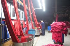 people are standing around in a warehouse with red curtains on the walls and metal buckets full of items