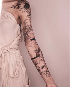 a woman's arm with tattoos on it and flowers in the middle of her arm