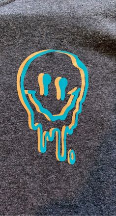 the back of a gray shirt with blue and yellow drips on it's chest