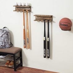 a basketball and baseball bats are hanging on the wall next to a bench with shoes