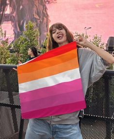 a woman holding up a rainbow colored flag