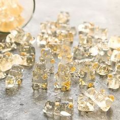 several pieces of ice sitting on top of a table next to a glass bowl filled with yellow liquid