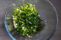 chopped green vegetables in a glass bowl on a wooden table