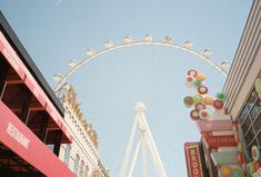 a ferris wheel in the middle of a shopping area with buildings and signs around it