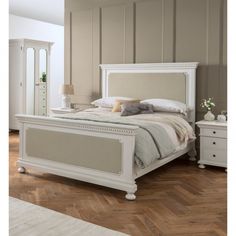 a white bed sitting on top of a wooden floor next to a dresser and mirror