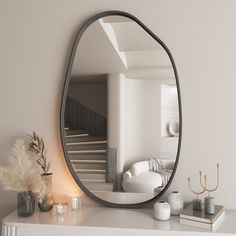 a mirror sitting on top of a white table next to a vase with flowers and candles