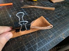 a pair of scissors is being used to make a leather case for a keychain