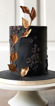 a black cake with gold leaves on top