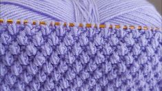 a close up view of a purple crochet pillow with yellow stitching on it