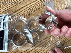 two hands holding clear plastic rings on top of a wooden table next to some money