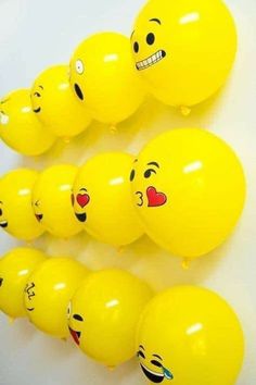 yellow balloons with smiley faces on them are lined up against a white wall in the shape of hearts