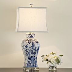 a blue and white vase sitting on top of a table next to a lamp shade