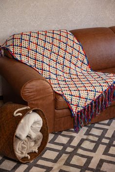 a couch with a blanket on top of it next to a basket filled with blankets