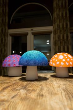 three colorful mushrooms sitting on top of a wooden table