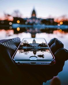 someone holding up their cell phone in front of the capitol building