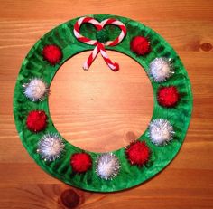 a paper plate wreath with pom - poms and candy canes on it