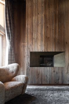 a living room with wood paneling and a chair in front of the window,