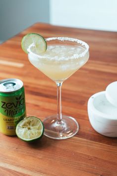 a margarita sitting on top of a wooden table next to a can