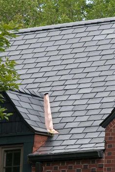 a brick building with a black roof and a white bird sitting on top of it