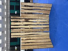 a wooden bench sitting on top of a blue wall next to a building with windows