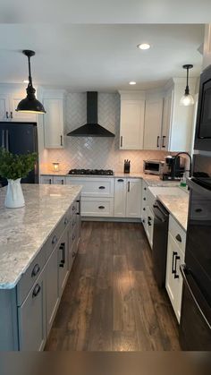 a large kitchen with white cabinets and black stove top ovens, an island in the middle