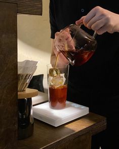 a man pours a drink into a glass on top of a white plate with ice