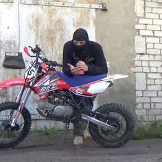 a man sitting on top of a dirt bike next to a building