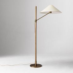 a floor lamp with a white shade on the base and a cord attached to it