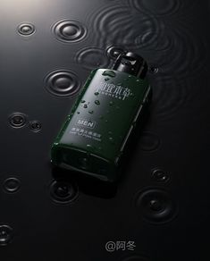 a green cell phone sitting on top of a black surface with water droplets around it