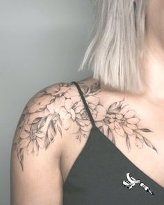 the back of a woman's shoulder with flowers tattooed on her arm and chest