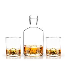 three glasses and a decante bottle with ice in them on a white background photo