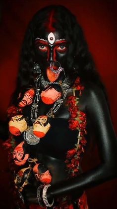 a woman with black skin and red makeup is dressed in an elaborate costume, holding her hands on her chest