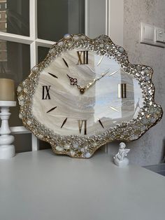 a decorative clock sitting on top of a white table next to a vase with flowers