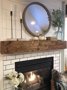 a fireplace with a mirror above it and some flowers on the mantle next to it