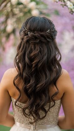 a woman with long hair wearing a wedding dress and flowers in her hair is looking down at the ground