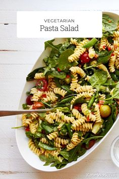 a white bowl filled with pasta salad on top of a table next to a fork