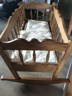 a wooden baby crib with white sheets on it