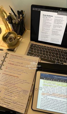 an open laptop computer sitting on top of a desk next to a notebook and tablet