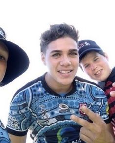 three young men are posing for the camera with one holding a cell phone in his hand