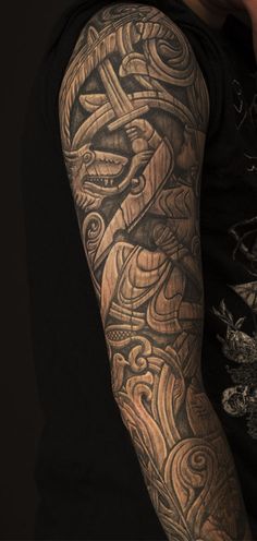 a man's arm with an intricate tattoo design on the sleeve and shoulder area