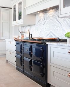 a kitchen with white cabinets and marble counter tops, an oven and stove top in the center