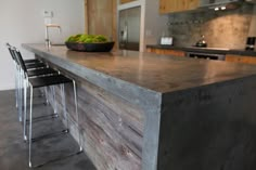 a kitchen with an island made out of wood and metal barstools in front of it