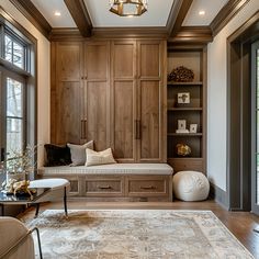 a living room filled with furniture and lots of wood paneled walls in front of large windows