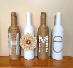 three wine bottles are decorated with flowers and monogrammed letters on top of a shelf