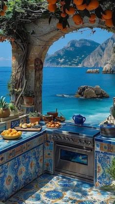 an outdoor kitchen with blue tile and oranges on the counter top, overlooking the ocean