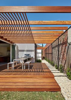 an outdoor patio with wooden decking and pergolated roof over the dining area