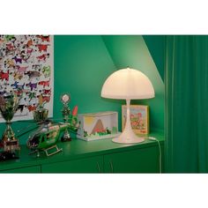 a green room with a lamp, pictures and other items on the dresser next to it